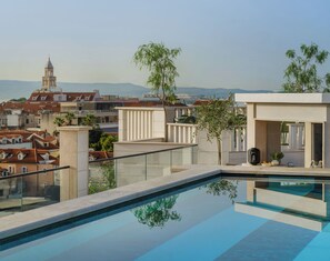 A rooftop pool with a clear view of the cityscape and distant mountains.