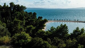 A coastal landscape with a beach, trees, and a clear sky. - Palazzo President (Split)
