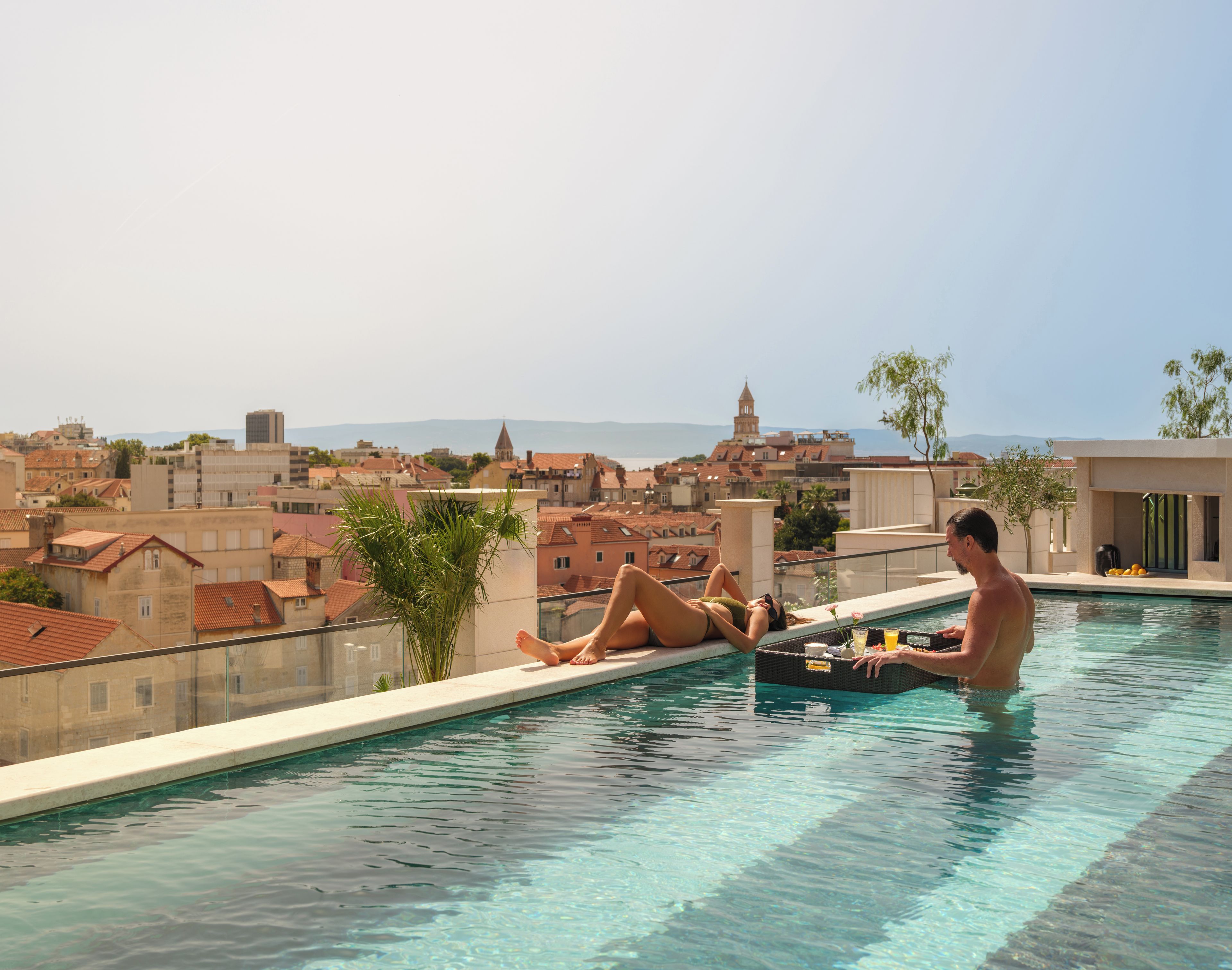 Une piscine sur le toit offrant une vue dégagée sur le paysage urbain, avec les bâtiments et une tour distante.
