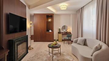 A modern living room with a flat-screen TV, a fireplace, a sofa, a desk with a chair, and a large wardrobe.