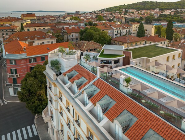 A high-rise building with a rooftop pool, terraces, and a view of the cityscape.