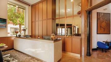 A reception area with a marble counter, wooden paneling, and a large window offering a view of the outdoors.