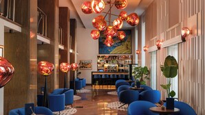 A modern lobby with blue seating, a bar area, and a unique chandelier. - Palazzo President (Split)