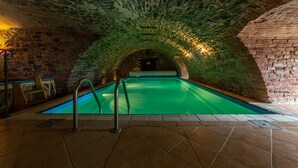 En indendørs swimmingpool med stenvægge og flisegulv.