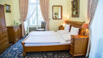 Une chambre à coucher bien rangée, avec un grand lit, une commode en bois, une table de chevet avec une lampe et une fenêtre avec des rideaux.