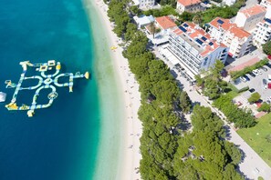 An aerial view of a coastal area with a beach, buildings, and a unique floating structure. - Villa Bondi (Makarska)