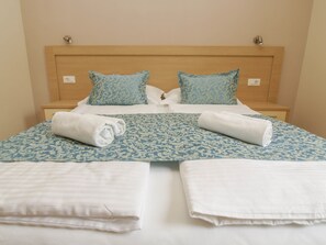 A neatly made bed with blue and white patterned bedding, two pillows with a similar design, and two rolled white towels on the bed. - Villa Bondi (Makarska)