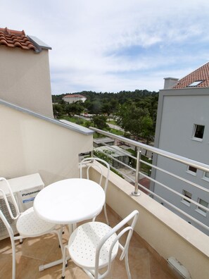 A balcony with a white table and chairs, overlooking a residential area with trees and buildings. - Villa Bondi (Makarska)