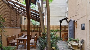 Un patio con muebles de madera, una pérgola y una maceta de piedra.