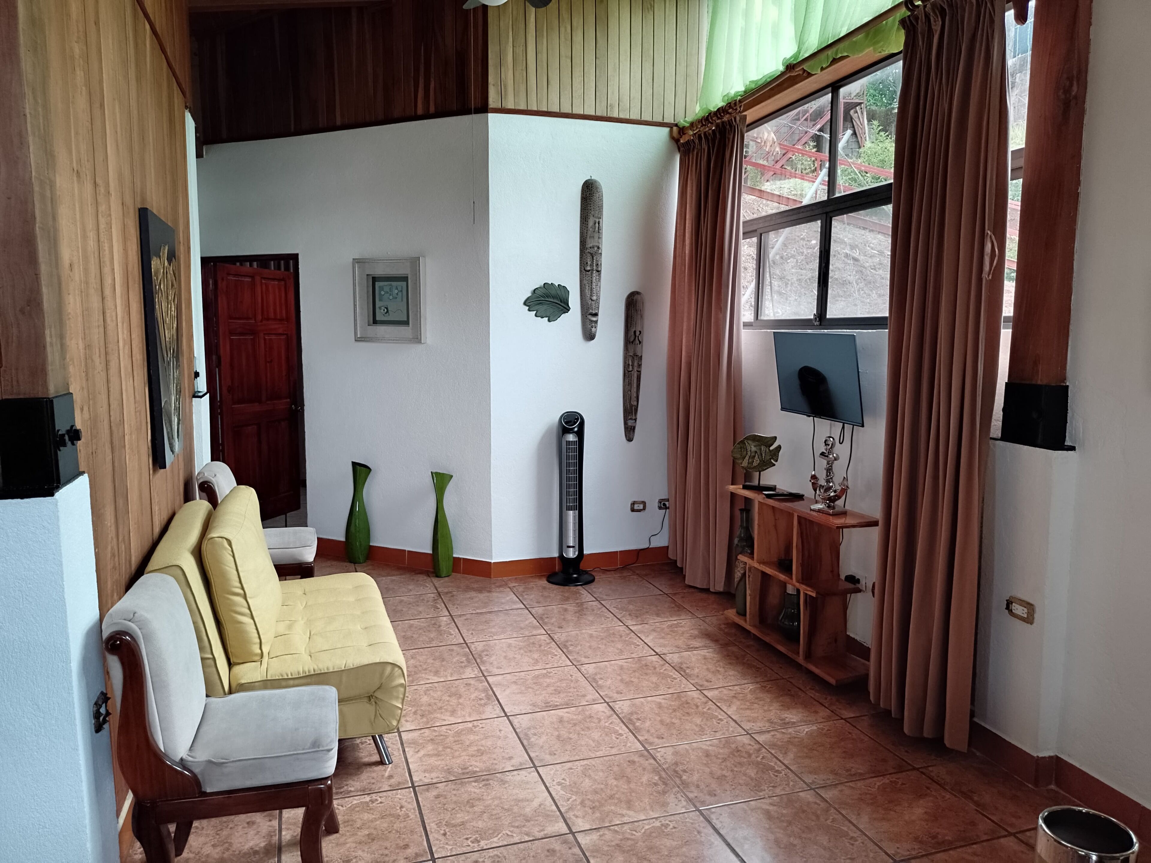 A living room with a sofa, a TV, a heater, and decorative items on the wall.