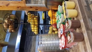 Een keukenhoek met een houten aanrecht, een metalen mand met brood, een bananenhanger en een plank met verpakte producten.