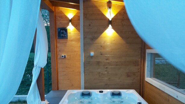 Een hottub met bedieningspaneel, omgeven door houten wanden en een raam.