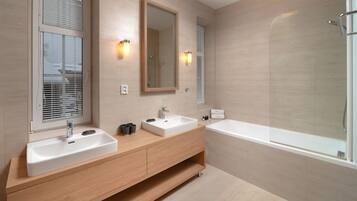 A modern bathroom with two sinks, a large mirror, and a bathtub.