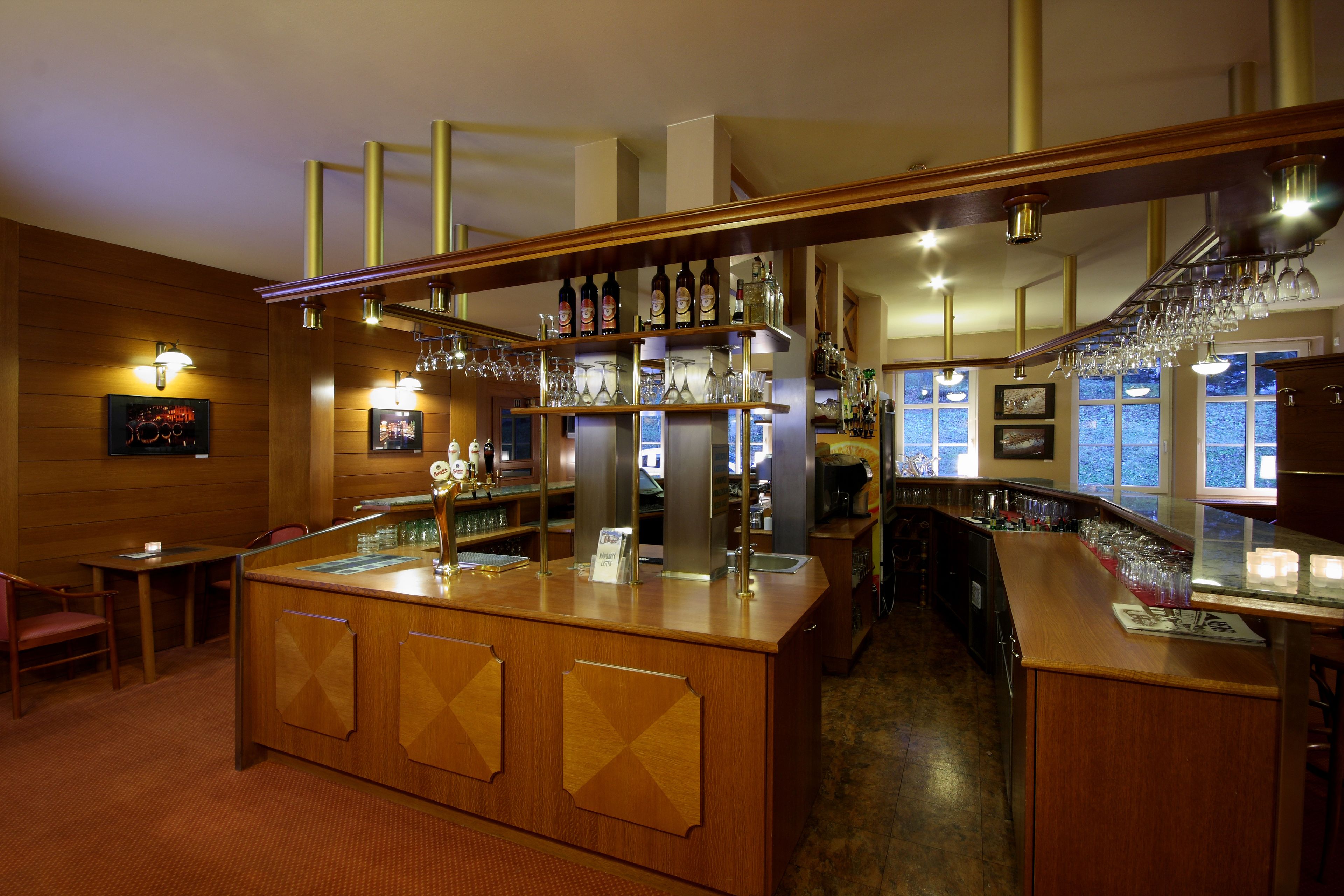 A bar area with wooden furnishings, shelves with bottles and glasses, and a counter with a menu.