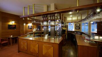 A bar area with wooden furnishings, shelves with bottles and glasses, and a counter with a menu.