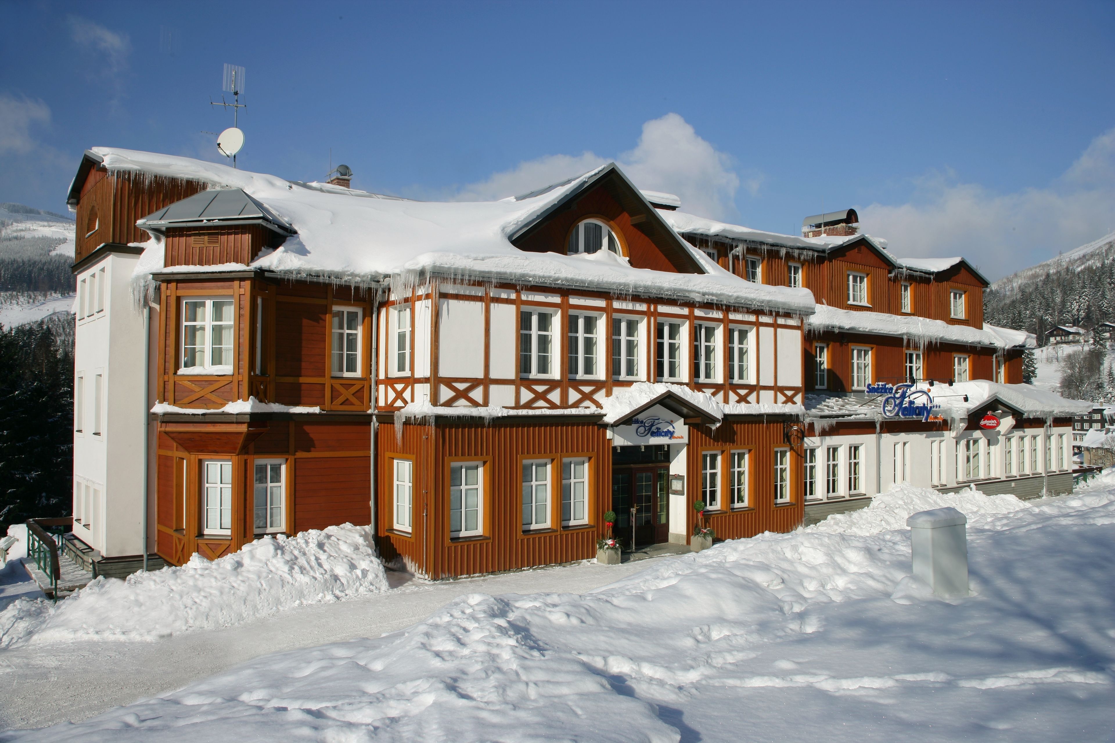 Un edificio grande de madera con varias ventanas y un techo cubierto de nieve, rodeado por nieve.