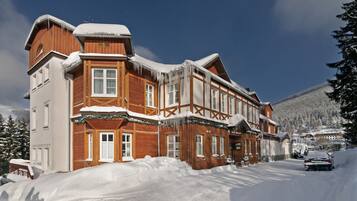 A large wooden building with multiple windows and a snow-covered roof, surrounded by snow.