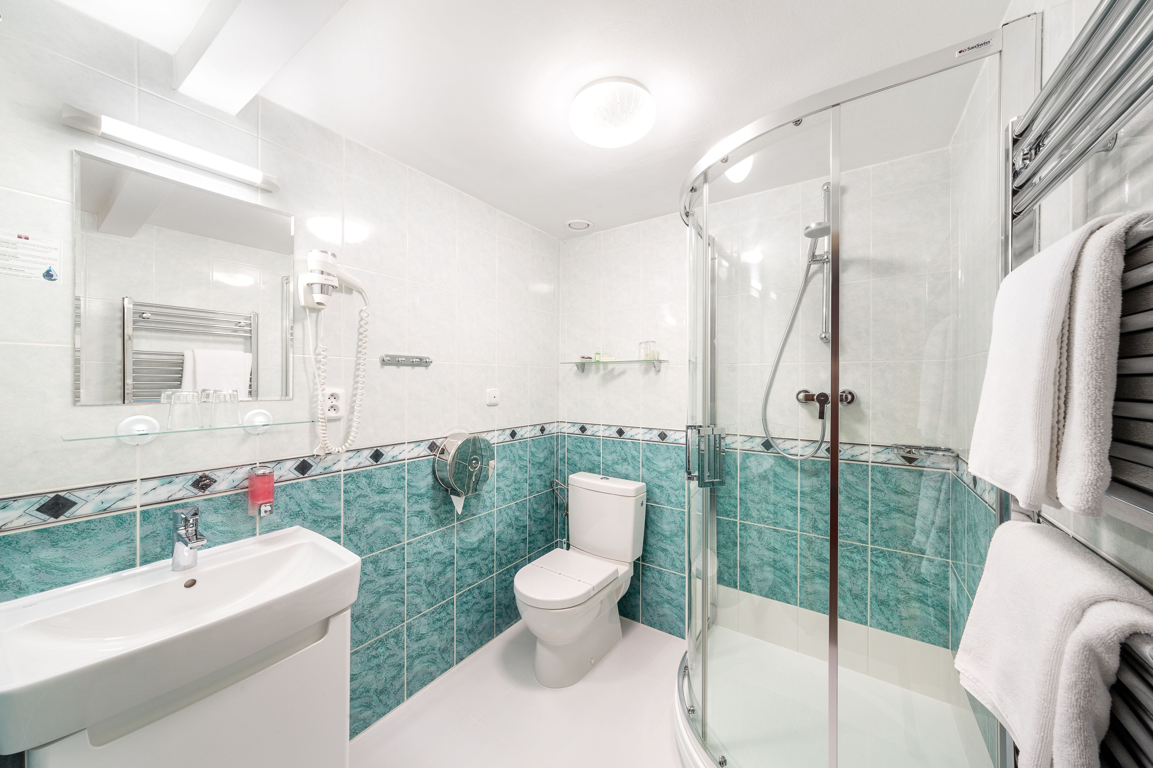 Ein modernes Badezimmer mit Duschkabine aus Glas, einem weißen Waschbecken und einer Toilette.