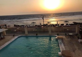 Una piscina con vistas al océano al atardecer.