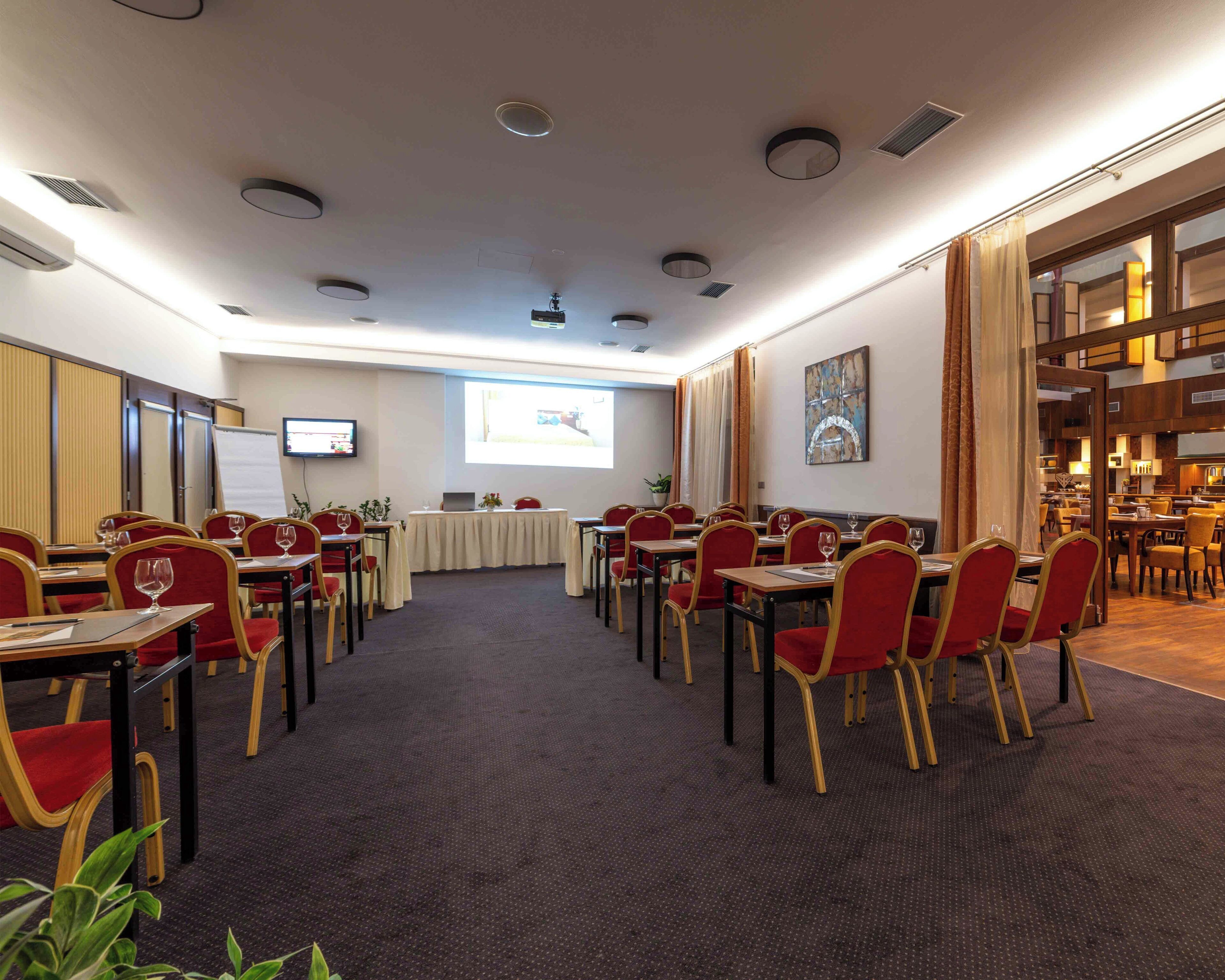 A conference room with tables and chairs, a projector screen, and a whiteboard.