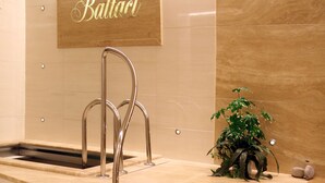 Ein modernes Badezimmer mit freistehender Badewanne, einem Holzschild über dem Waschbecken und einer Topfpflanze.