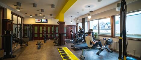 A gym with various exercise equipment, a treadmill, and a weight bench.