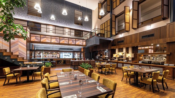 Ein geräumiges Restaurant mit verschiedenen Essbereichen, einer Bar und einer Treppe, die in einen oberen Bereich führt.