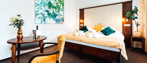 Hotelkamer met een groot bed, een ronde houten tafel, een stoel en een wanddecoratie.