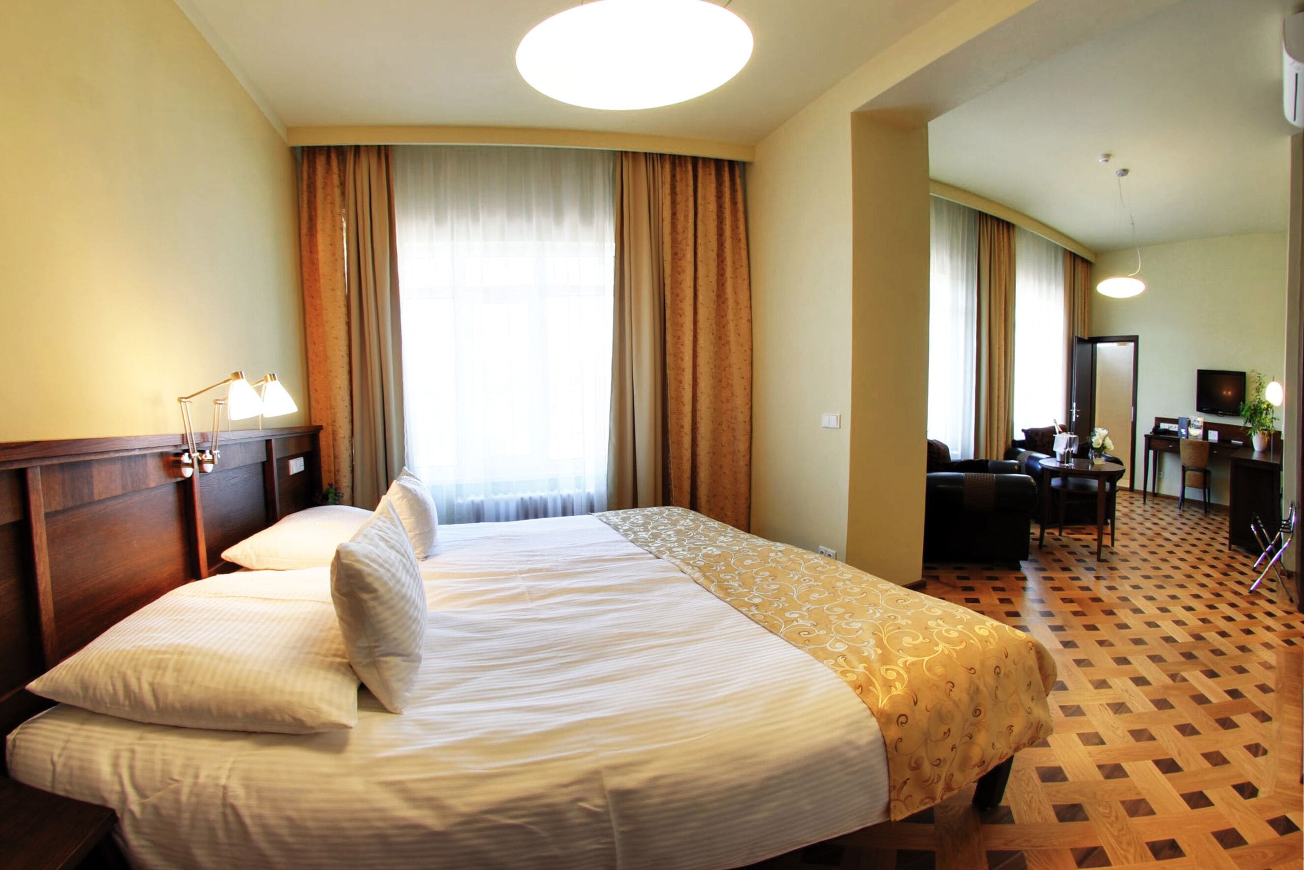 Una habitación de hotel con una cama grande, un escritorio con silla, televisor y un baño a la vista a través de una puerta abierta.