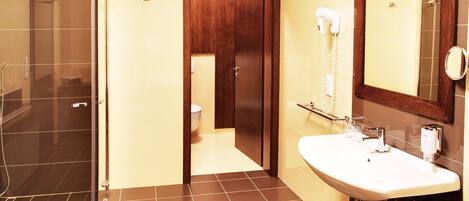 A bathroom with a shower, toilet, sink, and mirror.