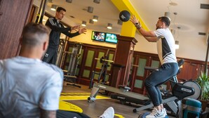 Ein Fitnessraum mit Trainingsgeräten, Holzwänden und einer gelben Akzentwand.