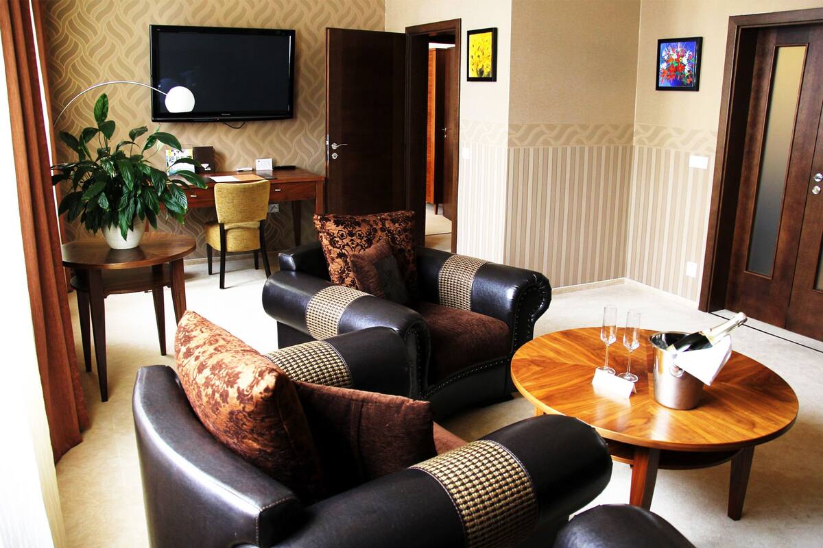 A living room with a sofa set, a coffee table, a TV, a plant, and a door.