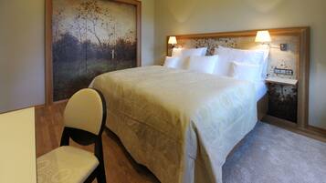 A bedroom with a bed, a chair, a nightstand, and a painting on the wall.