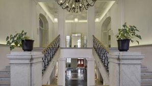 A grand staircase with ornate railings and potted plants at the top and bottom. - Chateau Herálec Boutique Hotel & Spa by L'OCCITANE (Heralec)