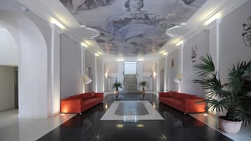 Eine geräumige Lobby mit einem polierten schwarzen Boden, roten Sofas, einem Teppich in der Mitte und einer Treppe zu einer oberen Ebene.