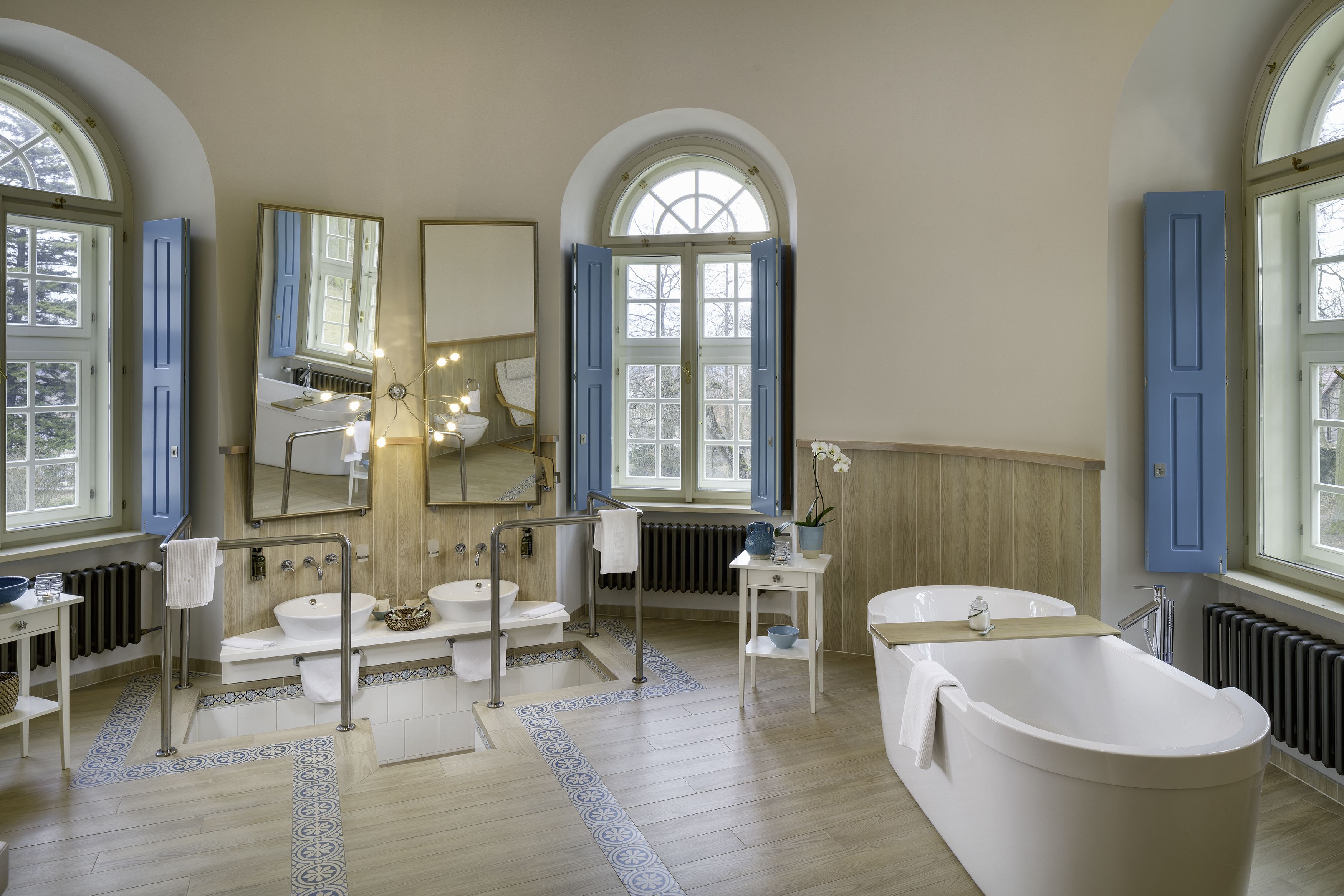 Un baño espacioso con una bañera independiente, un lavabo doble y un espejo grande.