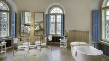 Un baño espacioso con una bañera independiente, un lavabo doble y un espejo grande.