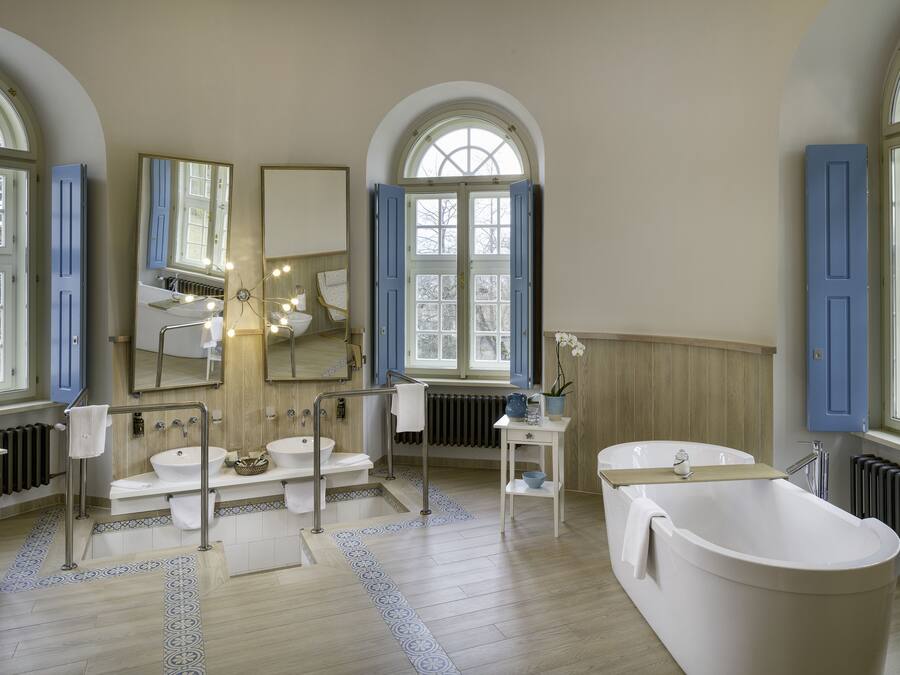 Un baño espacioso con una bañera independiente, un lavabo doble y un espejo grande.