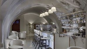A bar area with a marble wall, bar stools, and a variety of bottles and glasses. - Chateau Herálec Boutique Hotel & Spa by L'OCCITANE (Heralec)