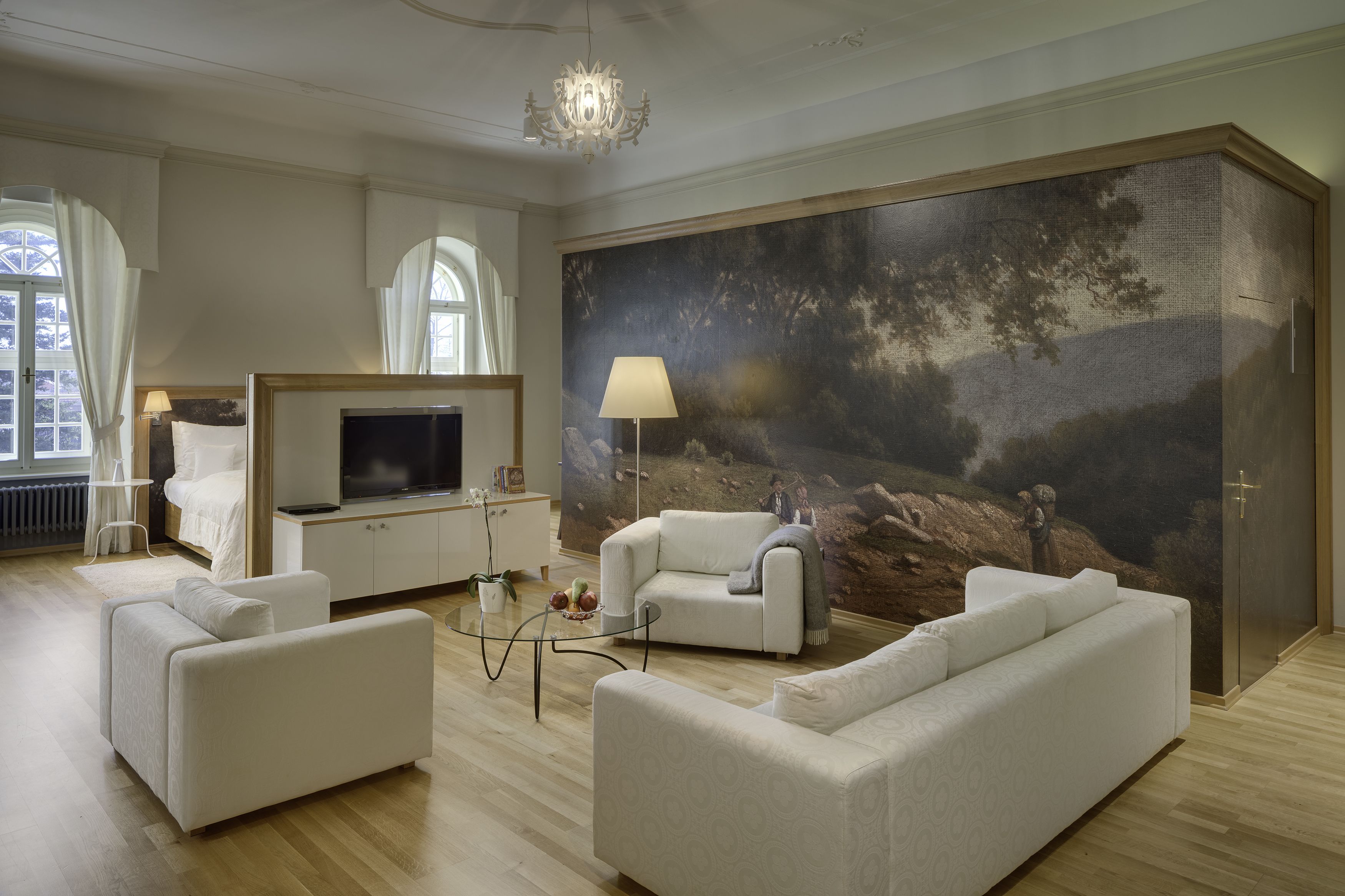A modern living room with a large painting, a flat-screen TV, and a cozy seating area.