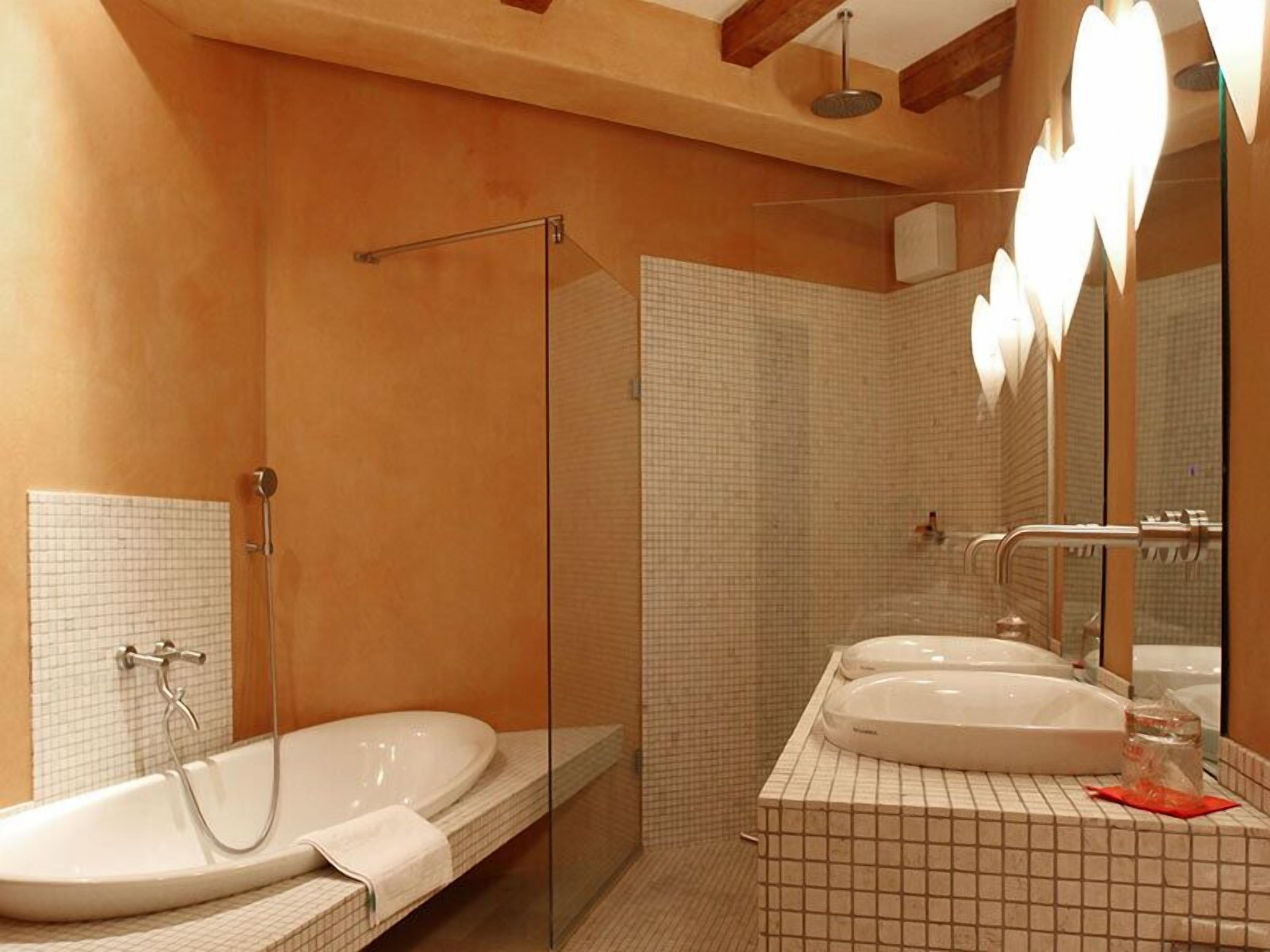 A modern bathroom with a glass-enclosed shower, a large bathtub, and a vanity with two sinks.