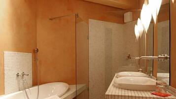 A modern bathroom with a glass-enclosed shower, a large bathtub, and a vanity with two sinks.