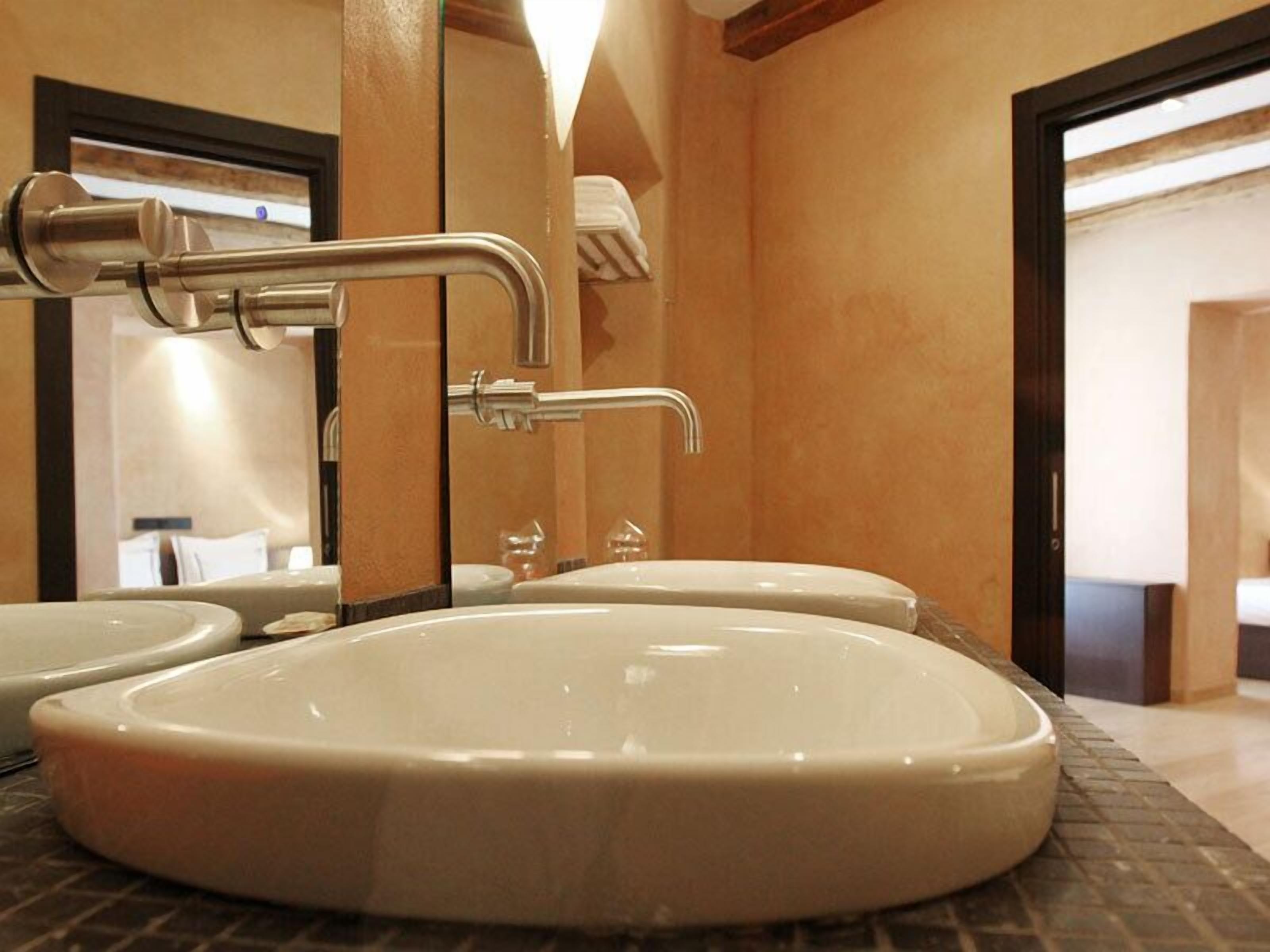 A bathroom with a large oval sink, a mirror, and a towel rack.