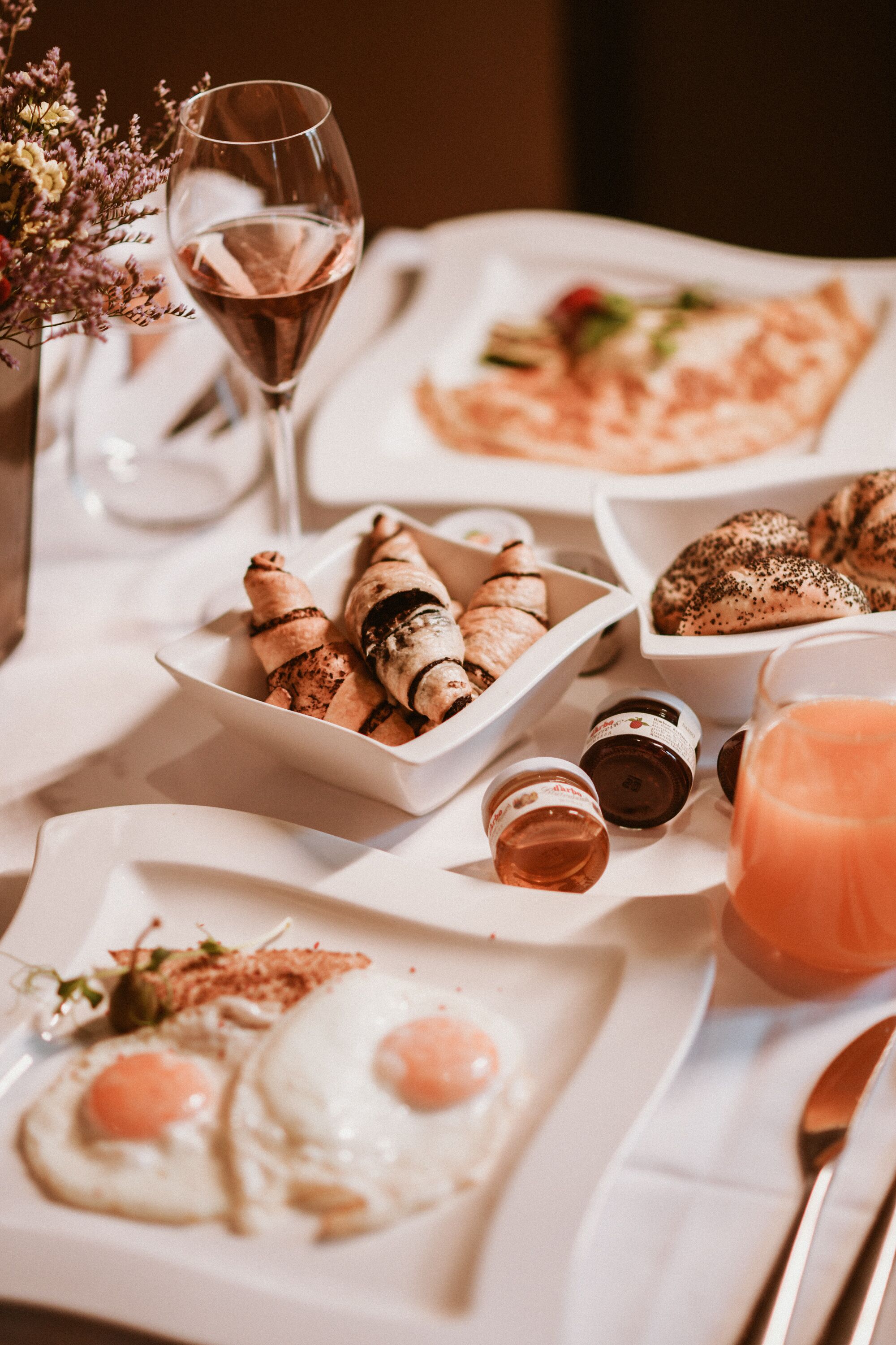 A table set with breakfast items including eggs, croissants, and a glass of juice.
