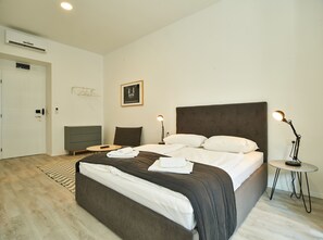Una camera d'albergo moderna con un letto grande, comodini, una scrivania e un condizionatore d'aria.
