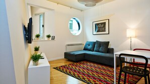 A modern living room with a sectional sofa, a colorful rug, a round mirror, and a framed quote on the wall.
