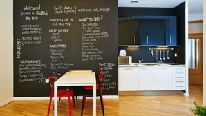 A modern kitchen with a blackboard listing breakfast options, bars, restaurants, and local attractions.