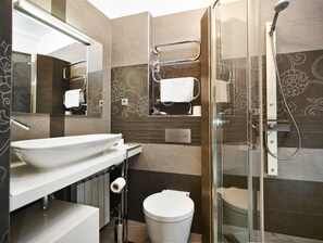 Une salle de bain moderne avec une douche à l’italienne en verre, un lavabo blanc et des toilettes.