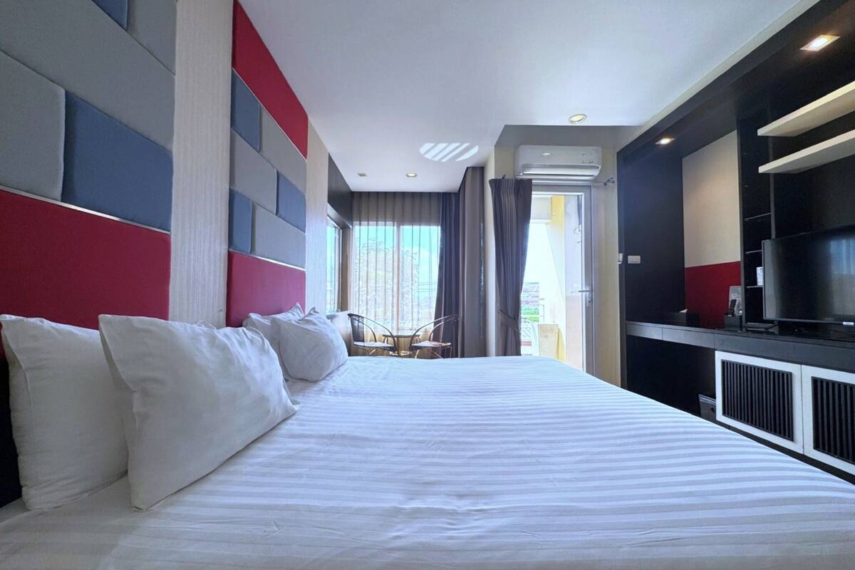 Hotellihuone, jossa on suuri sänky, televisio ja näkymä ulos.