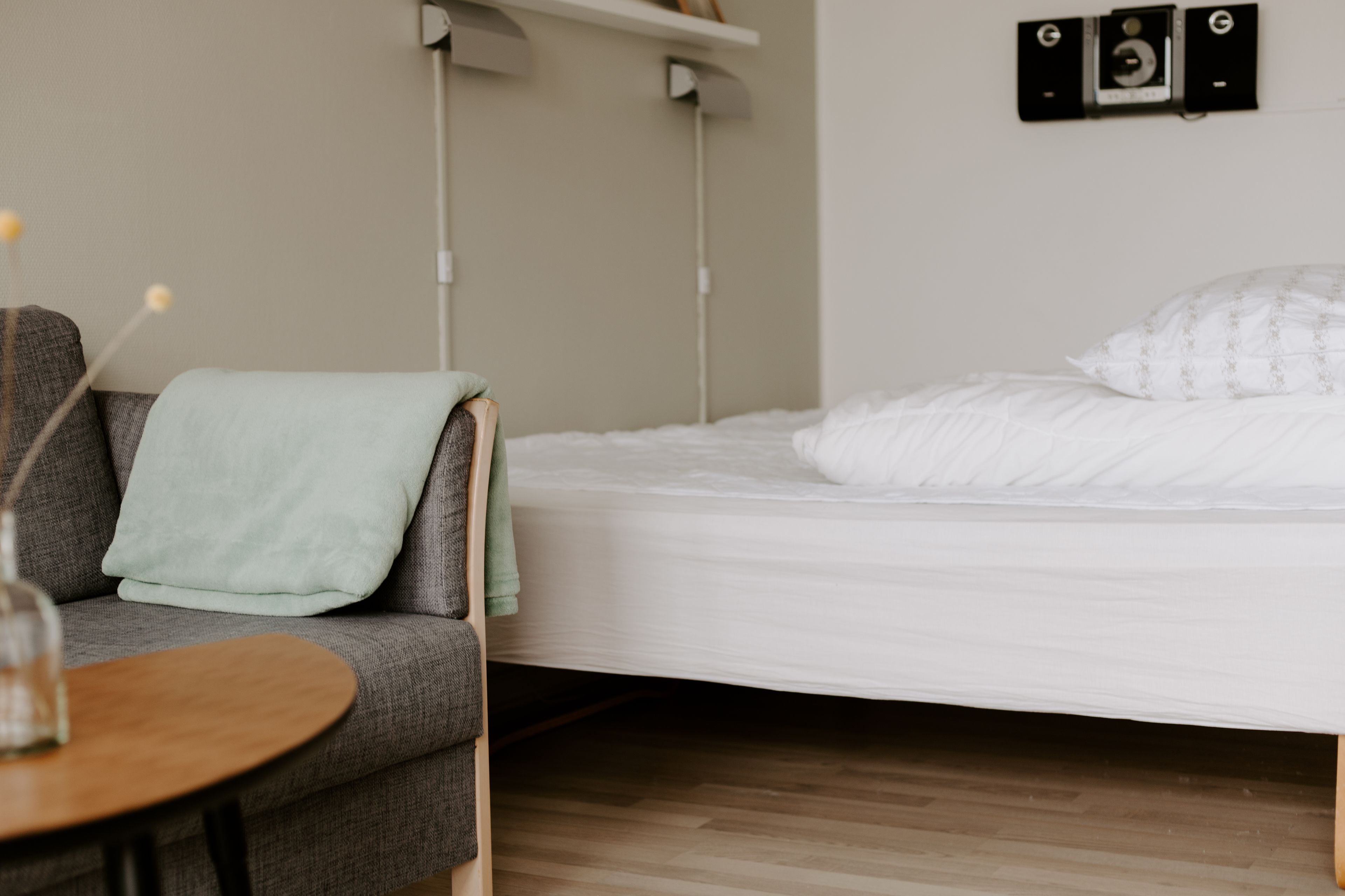 Une pièce comprenant un lit, un canapé, une petite table et un luminaire fixé au mur.